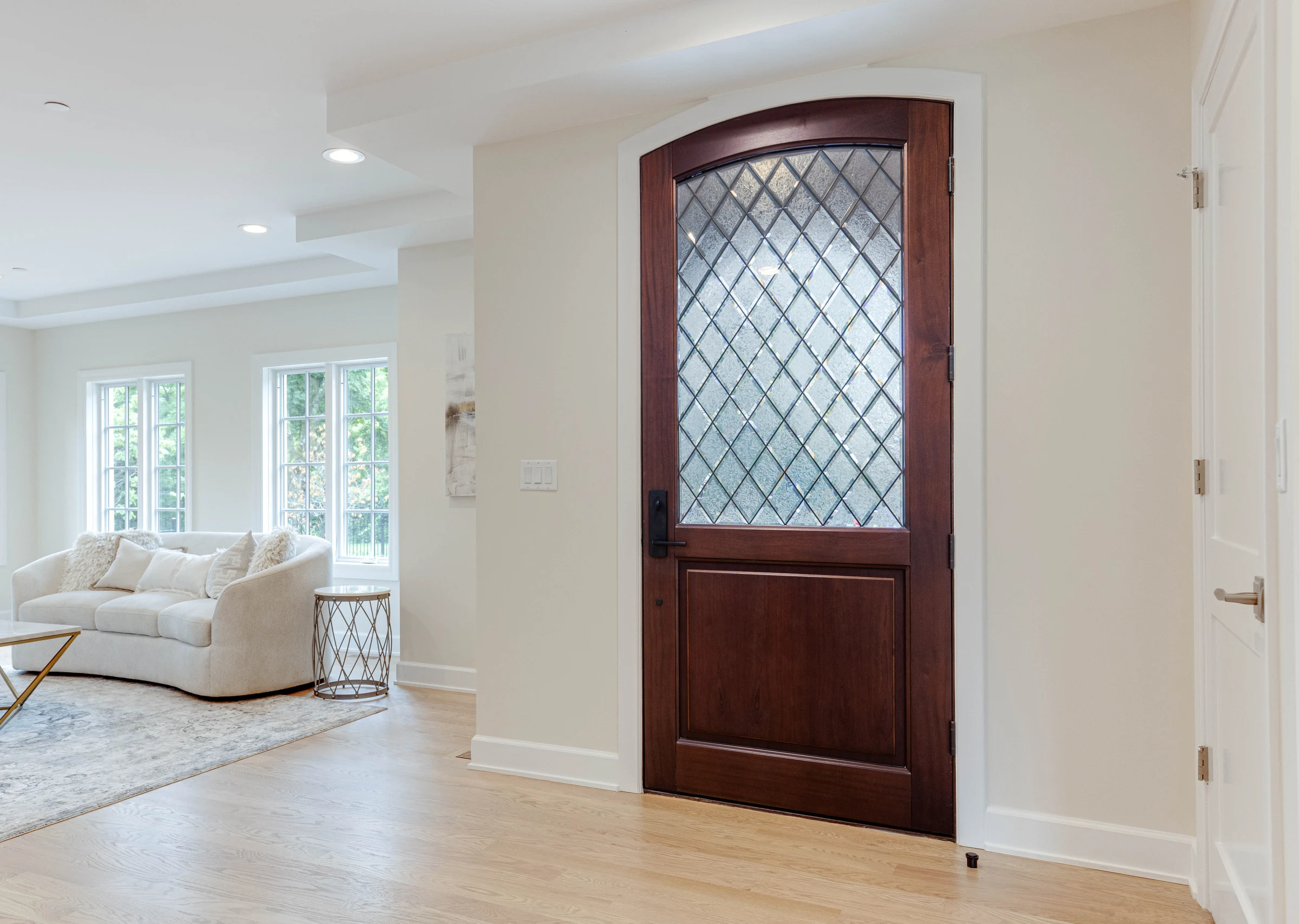 Arched carved-walnut door with leaded glass, framing the foyer and living room