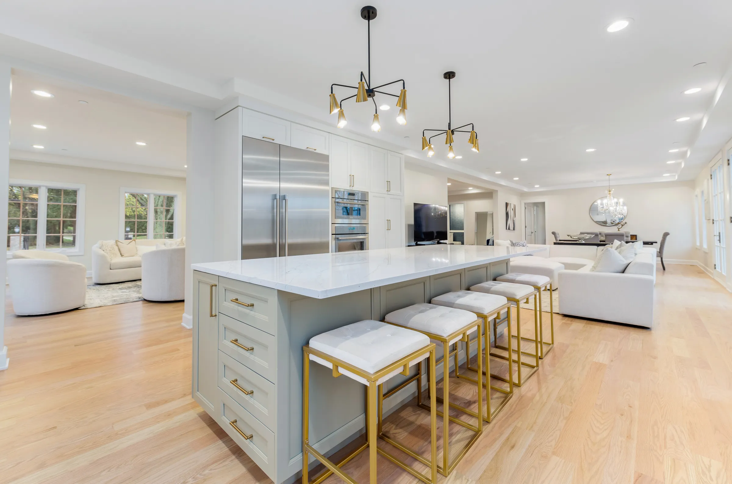 Kitchen with a long island, brass bar stools and glass pendant lights