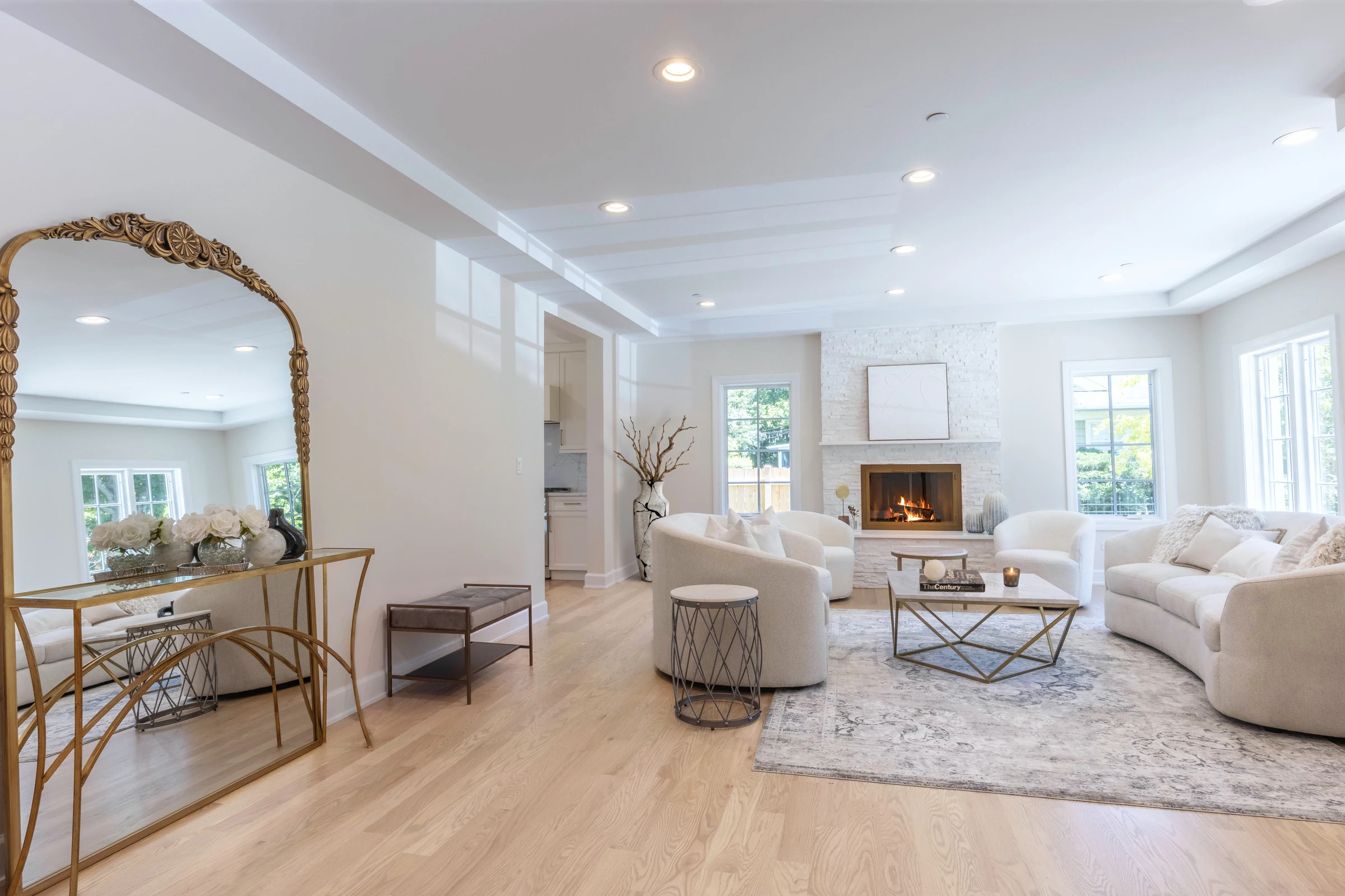 Bright living room with a lit fireplace, gilded mirror and curved seating